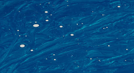 Creative metalic blue background and white dots made of paint and nail polish.