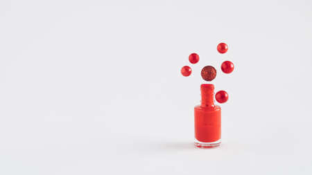 A creative idea of red Christmas decoration balls come out of red nail polish on white background....