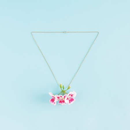 Creative idea of necklace and pink blooming flowers as pendant. Minimal jewelry flat lay concept.