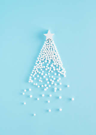 Creative Christmas tree arrangement made of white pearls and wooden star on a blue backgorund. Minimal 
New Year concept.の写真素材