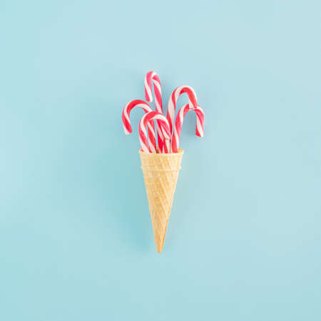 Creative arrangement made of an ice cream cone and Christmas sticks on a blue background. Minimal New Year concept. Summer Christmas inspiration.の写真素材