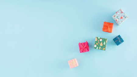 Christmas arrangement made of colorful gifts on a pastel blue background with copy space. Minimal...