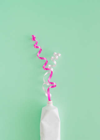 Creative arrangement made of decorative ribbons and tube of paint on a pastel green background. Gift...