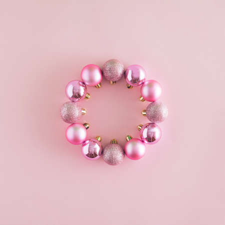 A creative Christmas arrangement made of baubles in the shape of a circle on a pastel pink background. Minimal New Year concept. Frame with copy space inspiration.の写真素材