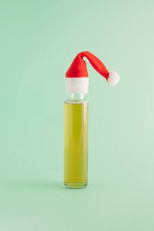 Creative arrangement made of a bottle of drink and red Christmas cap on a pastel green background. Minimal New Year concept. Santa and party inspiration.の写真素材