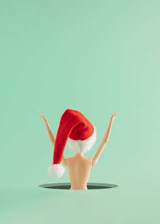 Creative Christmas arrangement made of a girl with a red Christmas hat on a mint green background....