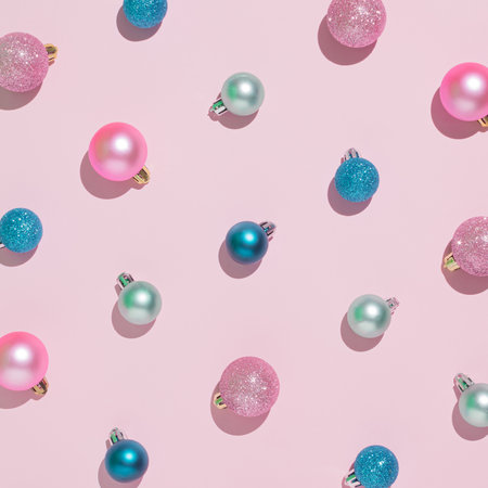 Creative Christmas pattern made of colorful Christmas baubles on a pastel pink background. Minimal New Year flat lay concept.の写真素材