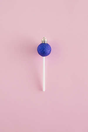 Creative arrangement made of vivid blue Christmas bauble and lollipop stick on a pastel pink background. Minimal New Year flat lay concept. Candy inspiration..の写真素材