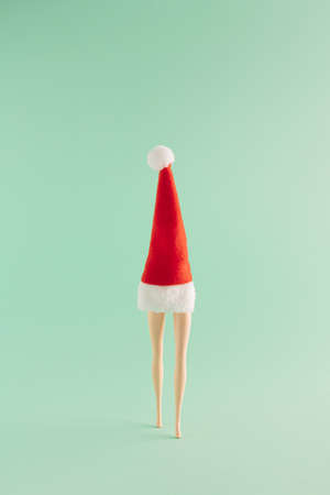 Creative Christmas arrangement made of red Christmas hat and legs on a mint green background. Minimal New Year concept. Santa Claus inspiration.の写真素材