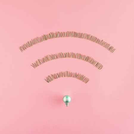 Wireless network symbol made of  pine needles shaped into WiFi symbol on a pastel pink background. Minimal internet technology idea. Flat lay winter concept. Christmas and december inspiration.の写真素材