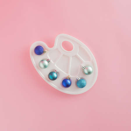 Creative arrangement made of painting palette and baubles on a pastel pink background. Minimal New...