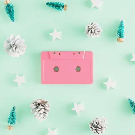 Creative Christmas arrangement made of a pink retro audio cassette and New Year's things on a mint green  background. Minimal party concept. Vintage Christmas songs inspiration.の写真素材