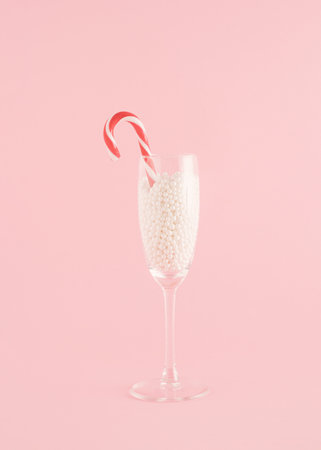 Creative Christmas arrangement made of a champagne glass with pearls on a pastel pink background. Minimal New Year concept. Candy party inspiration.の写真素材