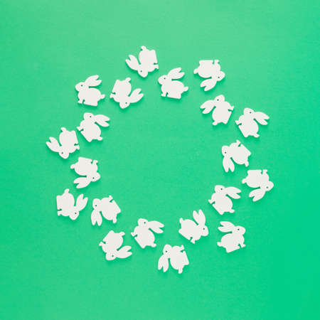 Round frame made of silhouettes of white rabbits on a green background. Minimal flat lay concept with copy space. Easter inspiration.の写真素材