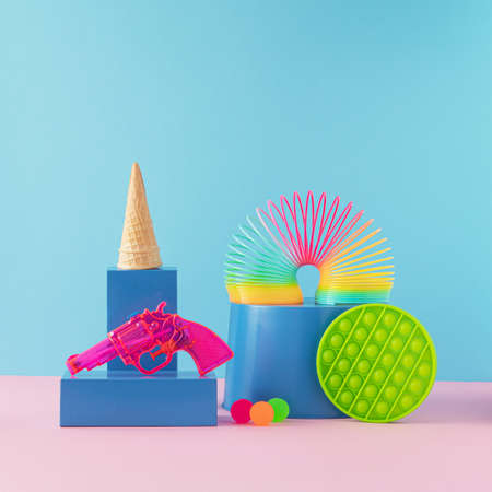 Creative arrangement made of colorful children's toys and cornet on a blue and pink background....