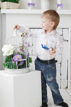 Beautiful happy blond boy holding in the room with a spring interiorの写真素材