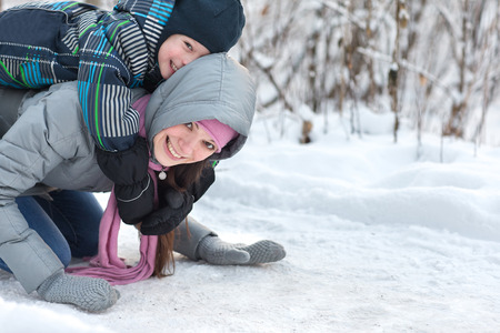 Beautiful young mother walking with her son in the winter forest.の写真素材