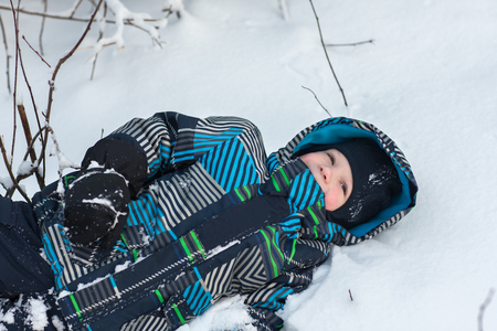 Happy boy walking and playing in the winter woods.の写真素材