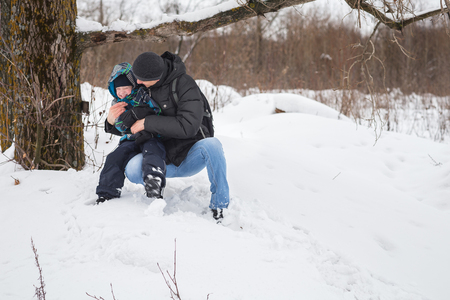Happy father and son walking in winter forest.の写真素材