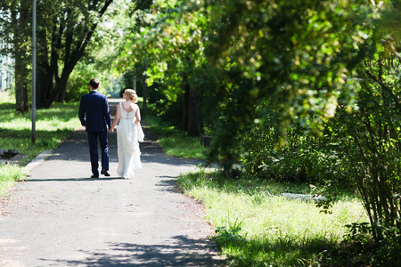 A happy young newly married couple walking in the park. Beautiful bride and groom kissing in the woods.の写真素材