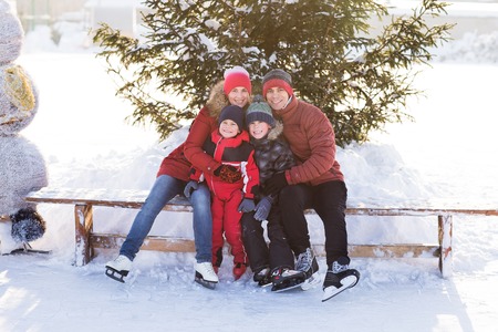 Happy young family skate at the rink in the winter. Beautiful family walking and playing on the ice in winter.の写真素材