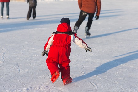 Happy child skating in winter at the rink. Cheerful children walk and play outside on the ice.の写真素材