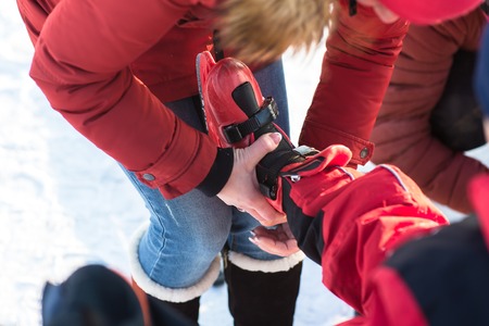 Parents put their children skating in winter on the street at the rink. Happy family skating.の写真素材