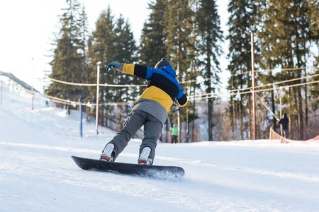 Male snowboarder laying turns on the ski slope. Snowboarder coming down from the mountain in winter.