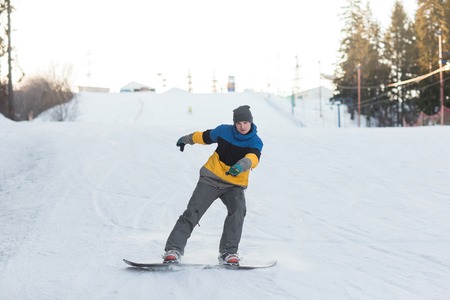Male snowboarder laying turns on the ski slope. Snowboarder coming down from the mountain in winter.の写真素材