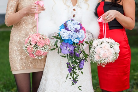 three young bridesmaids holding wedding bouquets outdoorの写真素材