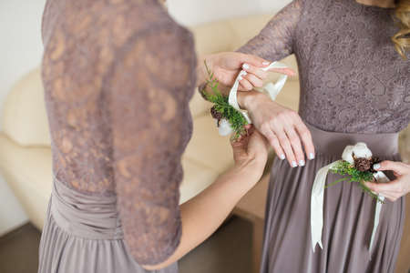 bride putting boutonniere on bridesmaid's hand in indoorの写真素材