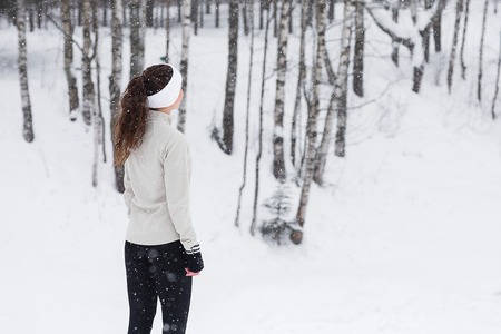 Sport woman running in winter. Female runner portrait in full body jogging in snow on cold winter day.の写真素材