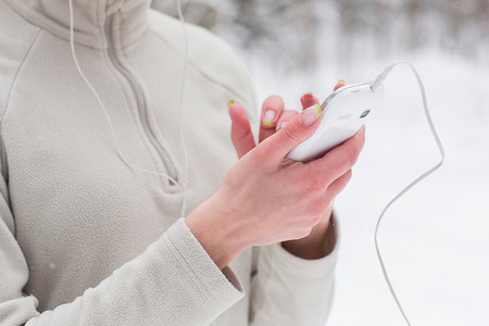 Young woman listening to music and jogging outside in winter. Trees in the snow. Weather snow cloud. Fitness on the street in the winter.の写真素材