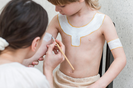 Blond boy playing injun. Child painted face paint and wearing a mask redskin.の写真素材