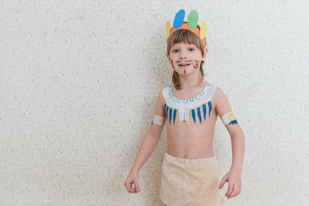 Blond boy playing injun. Child painted face paint and wearing a mask redskin.の写真素材