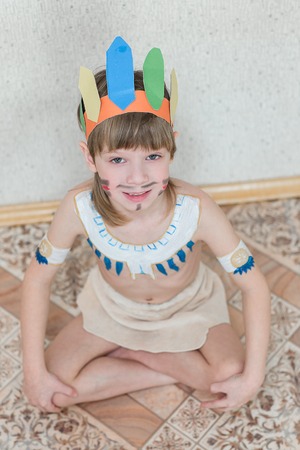 Blond boy playing injun. Child painted face paint and wearing a mask redskin.の写真素材