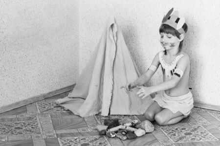 Blond boy playing injun. Child painted face paint and wearing a mask redskin.の写真素材