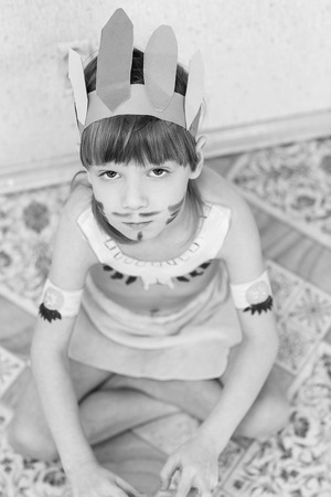 Blond boy playing injun. Child painted face paint and wearing a mask redskin.の写真素材