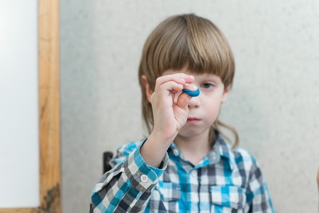 Blond boy holding sculpts from clay at homeの写真素材