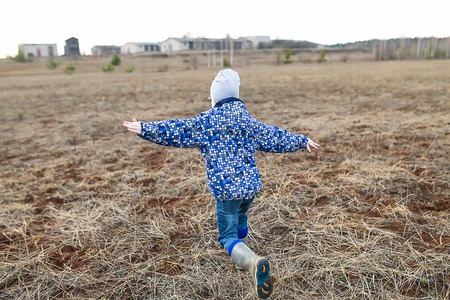 Kid run on field against autumn sky background.の写真素材