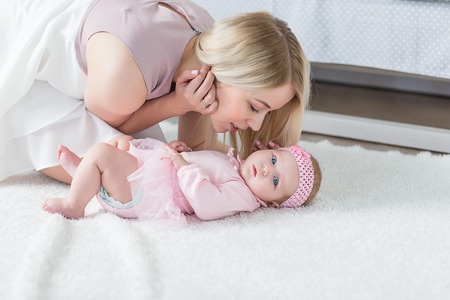 Young beautiful mother playing with her baby.