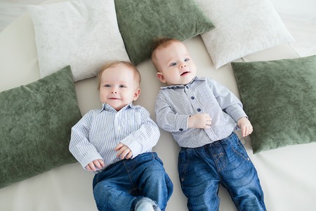 Funny baby boy twins playing on the floor in the nursery.の写真素材