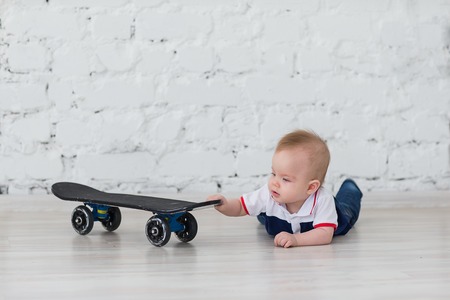 The little boy was crawling on the floor to the skateboard.の写真素材