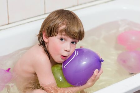 Happy handsome child boy bathes in a bathroom with balloons.の写真素材
