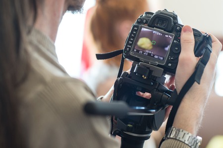 The photographer takes pictures of people in a professional photo studioの写真素材