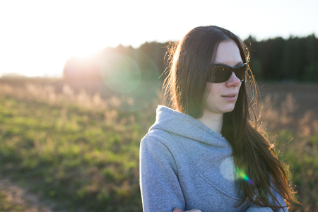 Beautiful young woman walking on a field at sunset.の写真素材