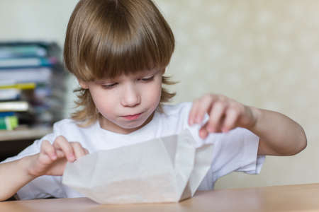 child opens a gift wrapped in white paper.の写真素材