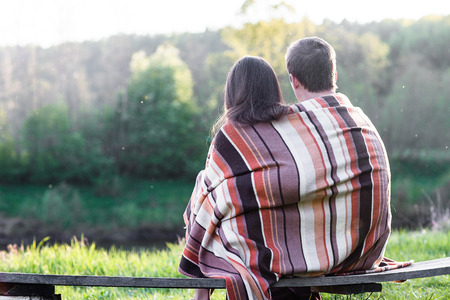 Loving couple sits on the bench over wonderful spring landscapeの写真素材