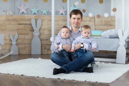 Portrait of dad with twin boys in the nursery.の写真素材