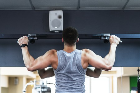 young bodybuilder training in the gym.  The man in the gym is tightened on the bar.